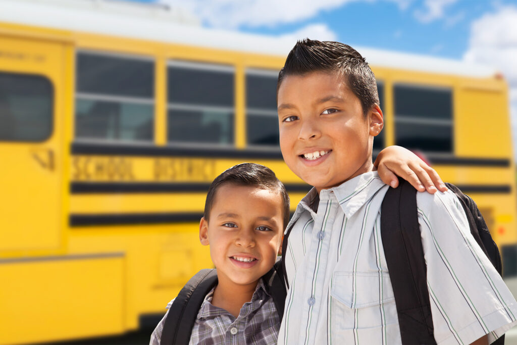 Young Hispanic Boys Walking Near School Bus